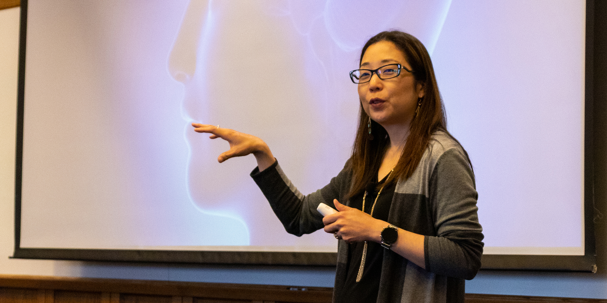 Michelle Weise gestures in front of a PowerPoint presentation