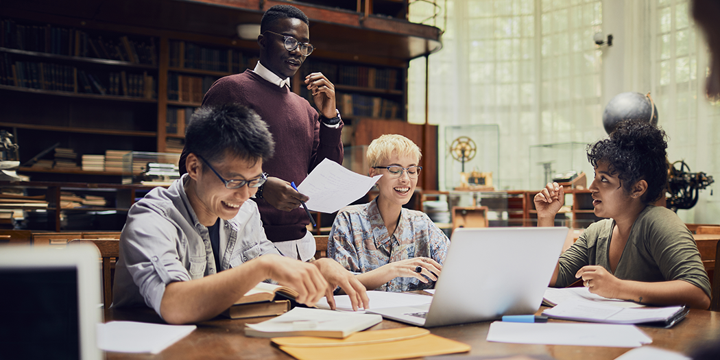 Students sit around a table in a library