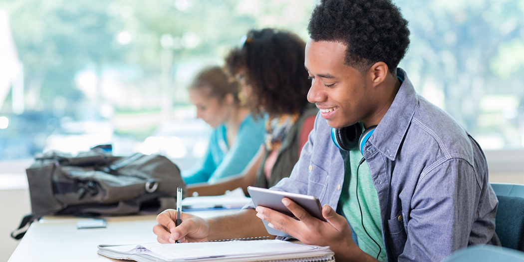 Black male college student taking notes in class