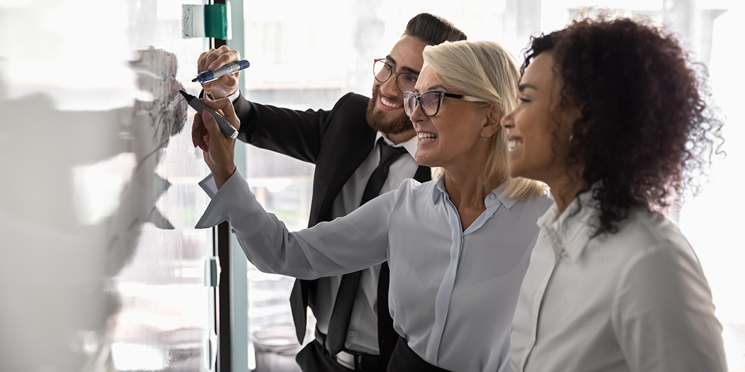 Smiling colleagues write on a white board