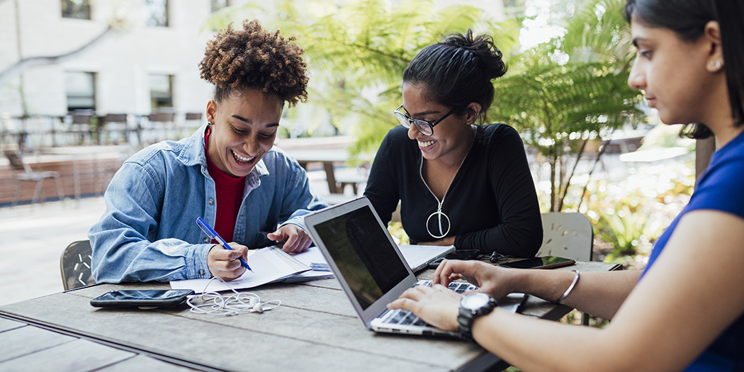 Three students smile and study together