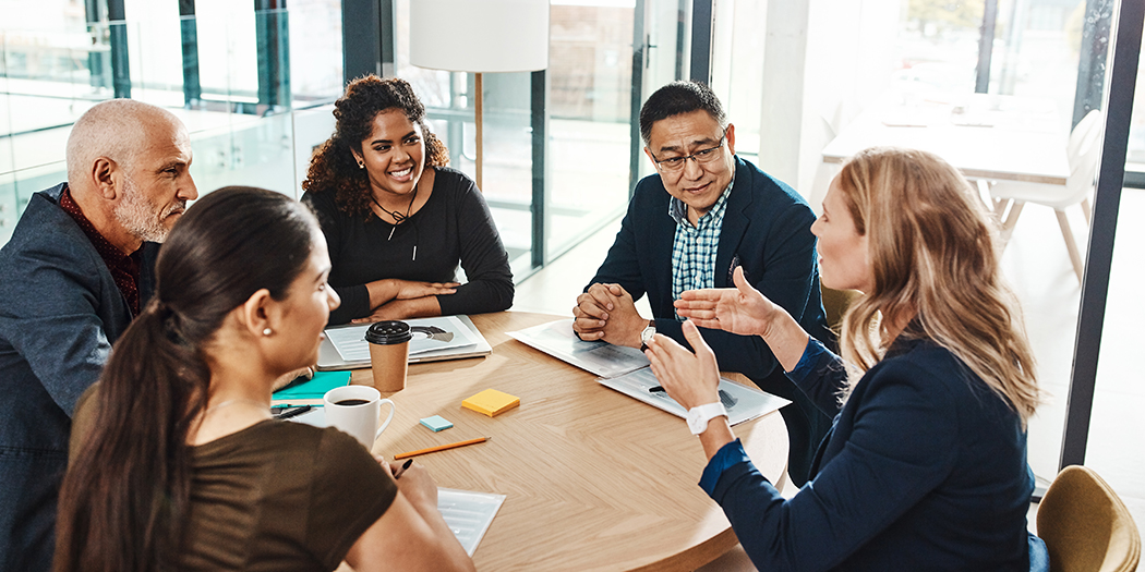 Adults sit around a conference table smiling