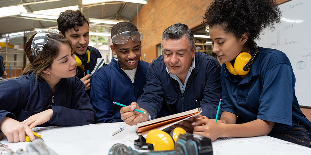 Manufacturing students gather around their instructor