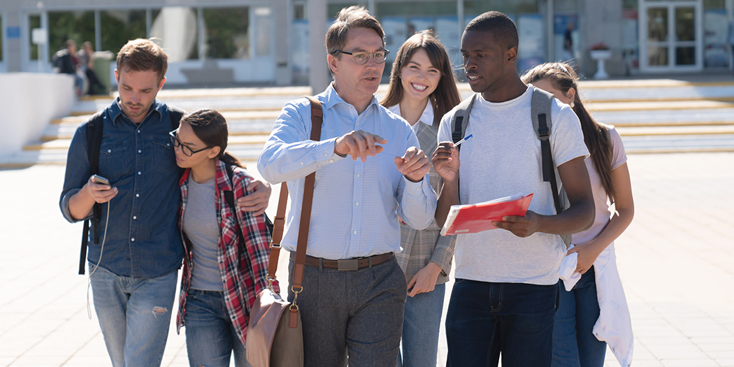 A group of students and a professor walk around campus