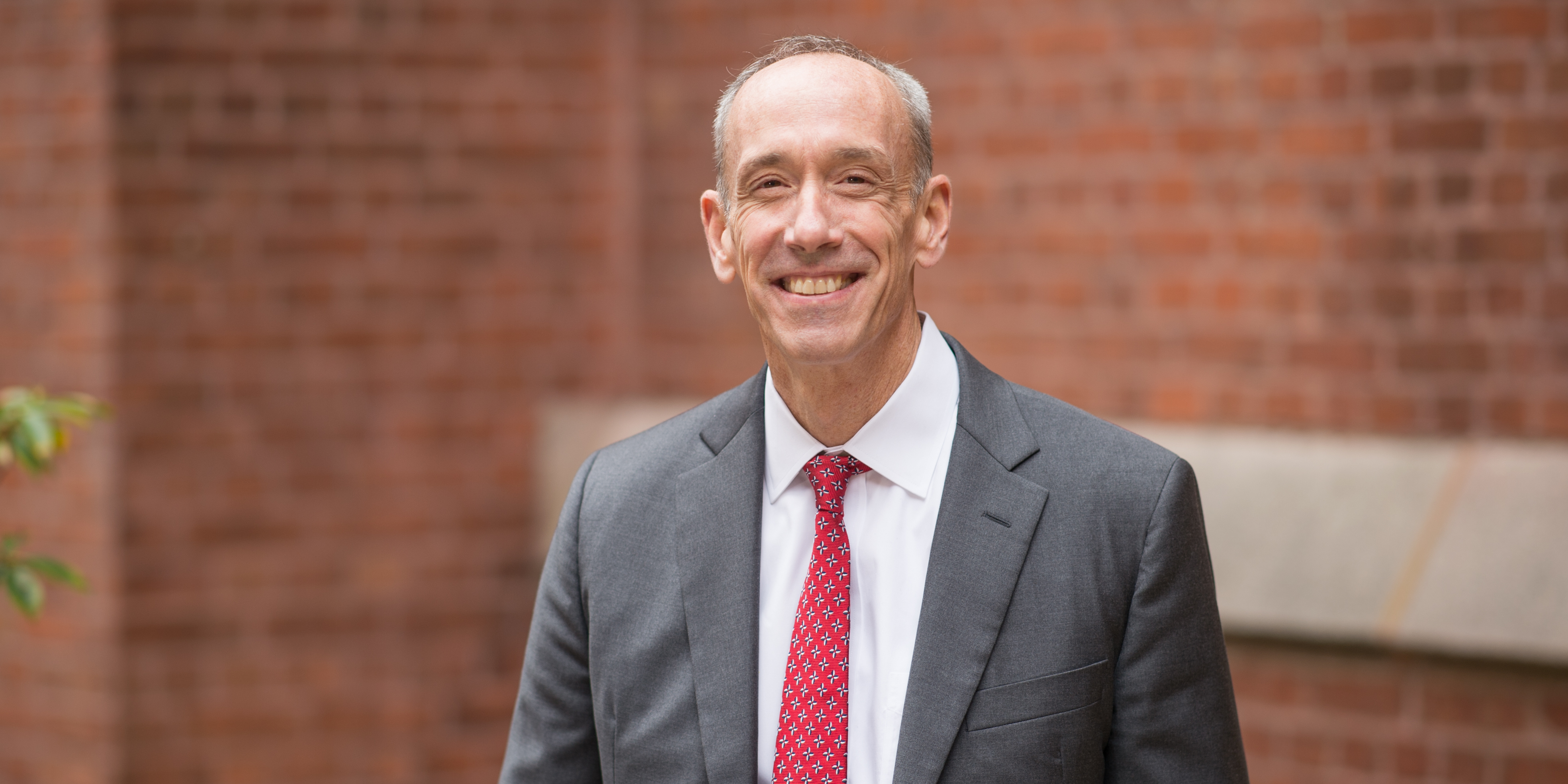 Thomas Brock smiles in front of a brick wall